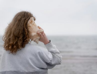 a woman holding a seashell up to her face