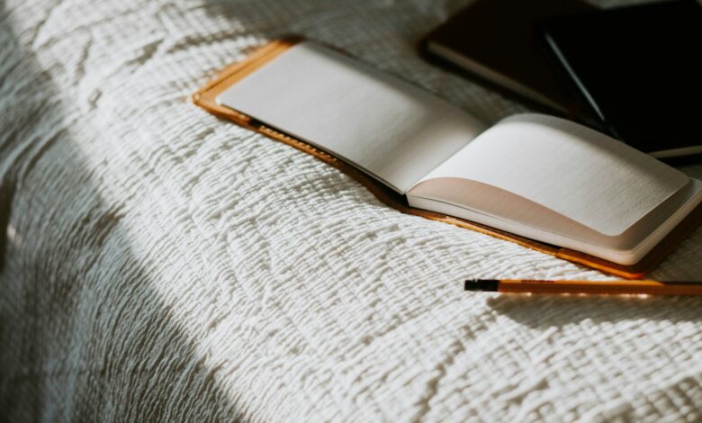 an open book sitting on top of a bed next to a pencil