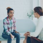 A woman talks to a therapist in an office.