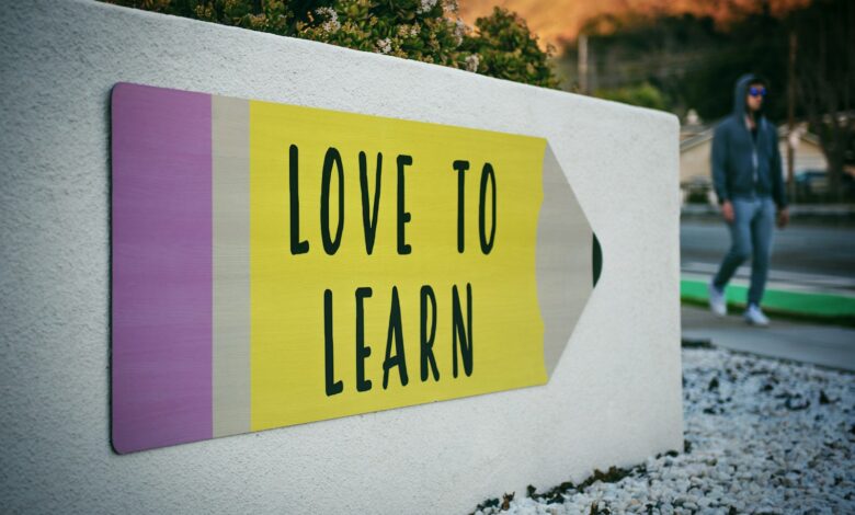 love to learn pencil signage on wall near walking man